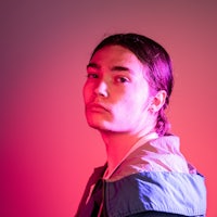 a man in a blue jacket standing in front of a red light